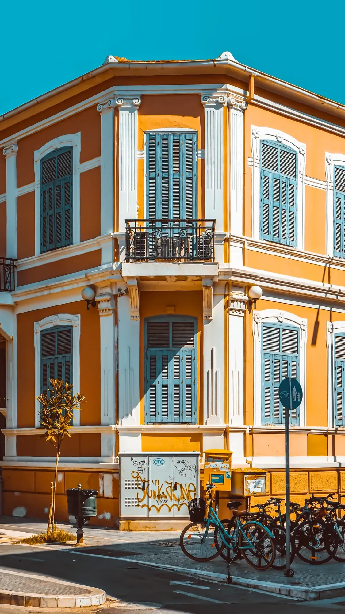 A colourful neoclassical corner building in central Alexandroupolis, with bicycles parked outside